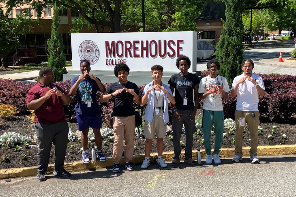 A group of students stand in front of the Morehouse College sign.
