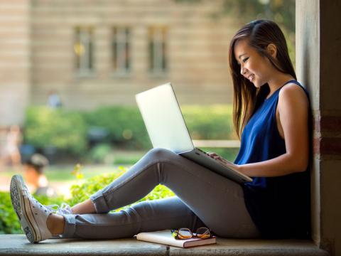 College student sitting in an opening on her laptop.