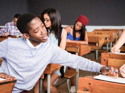 Young student assists another student with homework in class.