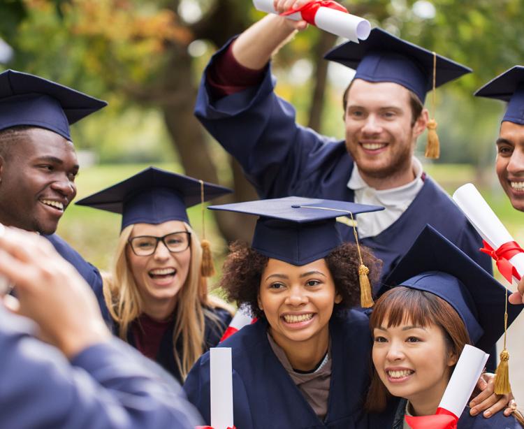 Group of recent graduates posing for a photo holding diplomas.