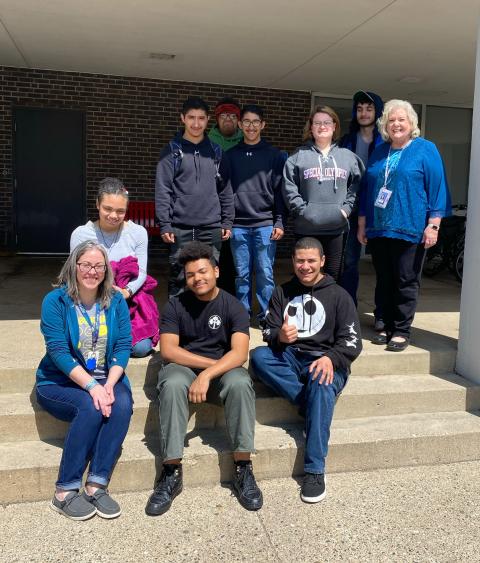 A group of students and staff sit on the steps in front of Saint Cloud State University.