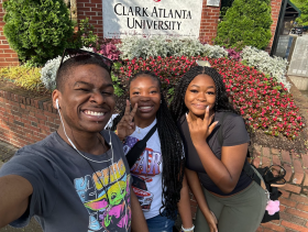 Three students post in front of the Clark Atlanta University sign during the HBCU tour.